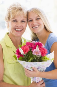 Granddaughter and grandmother holding flowers and smiling