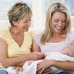 Grandmother and mother in living room with baby smiling