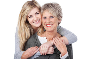 Happy Teenage Girl Embracing Grandmother From Behind
