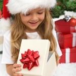 Little girl opening present in front of christmas tree - closeup