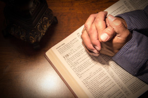 Praying hands on a bible